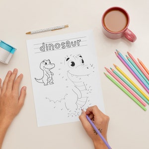 K&ouml;nnte beinhalten: Ein Kind verbindet die Punkte auf einer Malvorlage mit einem Dinosaurier. Die Seite ist mit "Dinosaurier" betitelt und enth&auml;lt eine kleine Dinosaurier-Illustration. Das Kind verwendet einen lila Stift, um die Punkte zu verbinden.