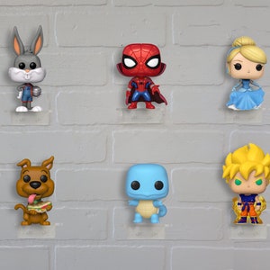 Op de afbeelding: Een verzameling van zes pop vinyl figuren die op een witte bakstenen muur worden getoond. De figuren omvatten Bugs Bunny in een basketbaluniform, Spiderman in zijn rood-blauwe pak, Assepoester in een blauwe jurk, Scooby Doo met een sandwich, een blauw dinosaurusachtig wezen en een blond anime-personage in een rood-oranje outfit.