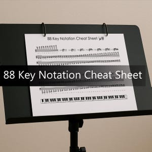 May include: A black music stand supports a white sheet of paper with musical notation and the text "88 Key Notation Cheat Sheet b/#". The title "88 Key Notation Cheat Sheet" is also printed in large white letters.