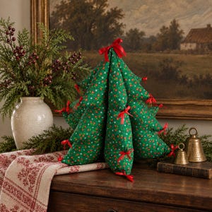 May include: A stuffed fabric Christmas tree in a green pattern with small red and white floral motifs. The tree features multiple tiers, each accented with small red ribbon bows tied at the tips of the branches, and a red ribbon bow at the top.