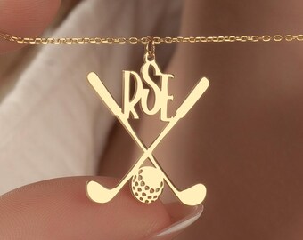 May include: Gold-colored necklace with a golf-themed pendant. The pendant features crossed golf clubs, a golf ball, and the initials "RSE". The necklace is displayed against a neutral background.