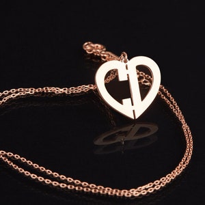 Peut inclure: Un collier en or rose avec un pendentif en forme de cœur orné des lettres "C" et "D" entrelacées.