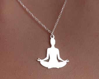 May include: A silver necklace with a pendant shaped like a person in a yoga pose.