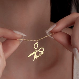 May include: Gold necklace with a scissor pendant and the name "Daisy" written on it.