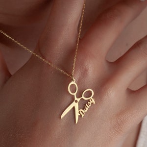 May include: Gold necklace with a scissor pendant and the name "Daisy" written on the blade.