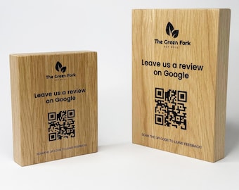 Op de afbeelding: Twee houten blokken met de tekst "The Green Fork" en "Leave us a review on Google" in het zwart gedrukt. Elk blok heeft een QR-code voor feedback. De blokken zijn gemaakt van lichtgekleurd hout.