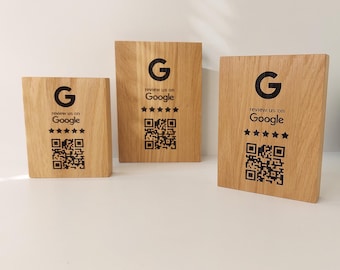 Op de afbeelding: Drie houten plaquettes met een zwarte 'G' en de tekst 'Review us on Google' met vijf sterren en een QR-code.