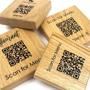 Könnte beinhalten: Vier quadratische Menühalter aus Holz mit QR-Codes und Text. Der Text enthält "menu", "Restaurant" und "Scan for Menu". Das Holz hat eine natürliche Maserung und eine hellbraune Farbe.