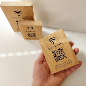 Op de afbeelding: Houten Wi-Fi toegangsborden met een zwart Wi-Fi symbool en de tekst "Scan for Wi-Fi". De borden tonen ook een QR-code en netwerkinformatie. De borden zijn van lichtgekleurd hout.