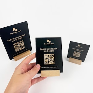 May include: Black table tent cards with gold text and QR codes. The cards read "The Green Fork" and "Leave us a review on Google." Each card is displayed in a wooden holder. The image is on a white background.