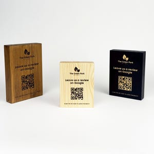 May include: Three wooden blocks with the text "The Green Fork, Leave us a review on Google" and a QR code. The blocks are in shades of brown, natural wood, and black. The blocks are rectangular and stand upright.