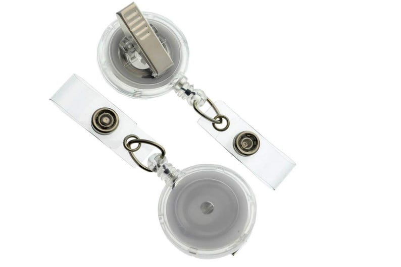 May include: Two clear plastic retractable badge holders with metal clips and clear plastic straps. The badge reels are round and have a silver-coloured centre. The straps have a snap closure.