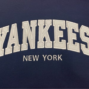 May include: A navy blue fabric patch with white embroidered text that reads "YANKEES NEW YORK".