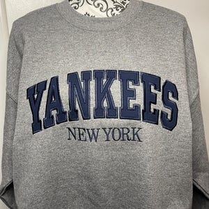 May include: Gray sweatshirt with a navy blue embroidered New York Yankees logo.