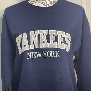 May include: A navy blue sweatshirt with the words "Yankees New York" embroidered in white on the front.