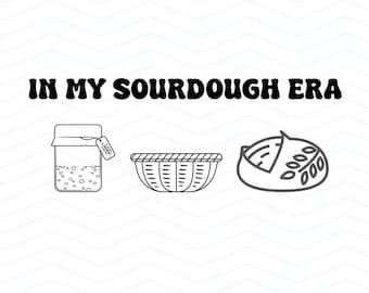May include: Black and white line art illustration with the text "IN MY SOURDOUGH ERA". The image includes a jar, a basket, and a loaf of bread, all in a simple, outlined style. The design suggests a theme of baking.