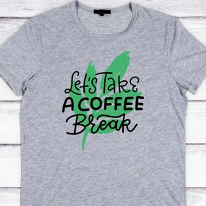 Może przedstawiać: Szara koszulka z zielonym wzorem liścia i napisem "Let's Take A Coffee Break" w kolorze czarnym.