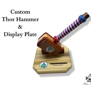 May include: A custom-made wooden Thor hammer with a red, white, and blue striped handle. The hammer is mounted on a wooden display plate with a seal and the text "Representative Charles A.  McKeon 87th House District".