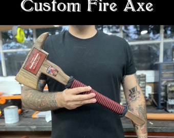 Può includere: Un'ascia da fuoco personalizzata con un manico in legno avvolto in paracord nero e rosso. La testa dell'ascia è in legno e ha una placca con il testo "Timothy Coleman" e un logo del corpo dei vigili del fuoco.
