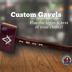 Könnte beinhalten: Ein individueller Hammer mit einem dunklen Holzgriff und einem rechteckigen Kopf. Der Kopf hat eine tief burgunderrote Farbe mit einem weißen Logo und dem Text "2023" auf dem Griff. Der Text "Custom Gavels" steht oben.