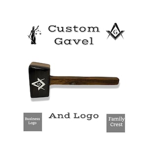 Może przedstawiać: Drewniany młotek z czarnym i srebrnym symbolem masońskim na głowie. Tekst "Custom Gavel And Logo" jest nadrukowany pod młotkiem.