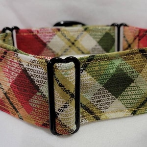 May include: A dog collar with a plaid pattern in shades of red, green, and gold. The collar has black hardware and a sturdy design. The plaid pattern features a diamond design.