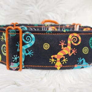 May include: A black dog collar with orange metal hardware features a colorful print of lizards on a black background.