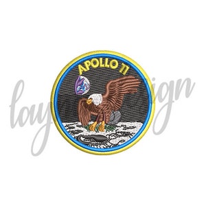 May include: A yellow, blue, and black embroidered patch with the text "Apollo II" and an image of an eagle landing on the moon.