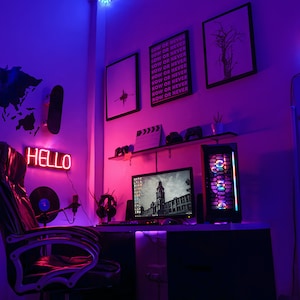May include: A gamer's room with a black gaming chair, a computer monitor, a keyboard, a mouse, a neon sign that says "HELLO", and a neon sign of a camera. The walls are painted purple and blue, and there is a world map sticker on the wall.