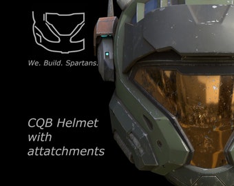 May include: A green and black helmet with a gold visor and attachments. The helmet has a worn and weathered look. The text "We. Build. Spartans." and "CQG Helmet with attachments" is visible in the image.