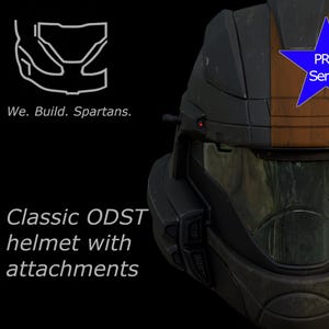 Puede incluir: Primer plano de un casco ODST gris oscuro y naranja con accesorios. El casco tiene una visera transparente y un emblema azul en forma de estrella que dice "PRO Series". También se ve el texto "We. Build. Spartans." y "Classic ODST helmet with attachments".
