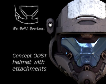 May include: A close-up of a gray and blue ODST helmet with attachments. The helmet has a visor and various mechanical details. The text "We. Build. Spartans." and "Concept ODST helmet with attachments" are also visible.