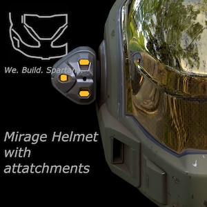 May include: A green and gold helmet with a visor and attachments. The helmet has a worn, weathered look. The text "Mirage Helmet with attachments" is visible below the helmet.