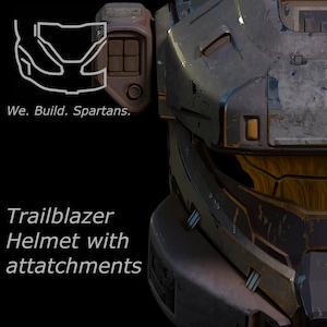 Könnte beinhalten: Nahaufnahme eines dunkelgrauen und schwarzen Helms mit gelbem Visier und einem abgenutzten, verwitterten Aussehen. Der Helm hat verschiedene Anbauteile und Details, darunter ein kleines gelbes Licht an der Seite. Der Text "Trailblazer Helmet with attachments" ist unterhalb des Helms sichtbar.