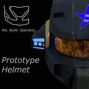 Può includere: Un casco prototipo nero con visiera dorata e dettagli blu. L'immagine include il testo "Prototype Helmet" e una stella blu con "PRO Series". È presente anche la frase "We. Build. Spartans."