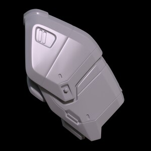 May include: A gray, textured, plastic piece with a geometric design. It has a rectangular shape with rounded edges and a series of raised lines and grooves.