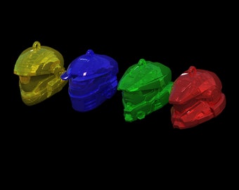 Könnte beinhalten: Vier Plastik-Anhänger in Form von Helmen in Gelb, Blau, Grün und Rot.