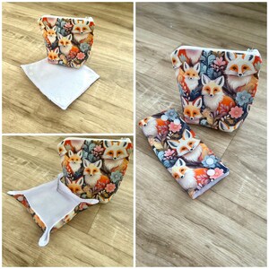 May include: A set of three items: a cosmetic bag, a small square tray, and a rectangular case. All items feature a repeating pattern of foxes, flowers, and foliage in shades of orange, white, and blue. The cosmetic bag has a zipper closure.
