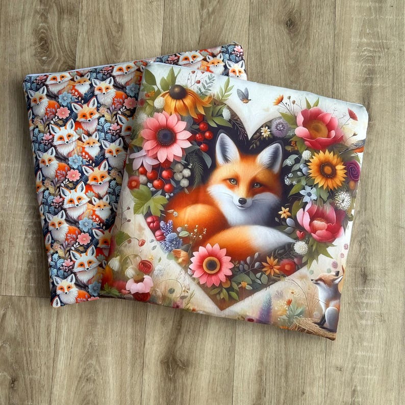 May include: Two decorative pillows. One features a repeating pattern of foxes with flowers in a variety of colors. The other pillow has a fox in the center of a heart-shaped floral arrangement with pink, orange, and yellow flowers.