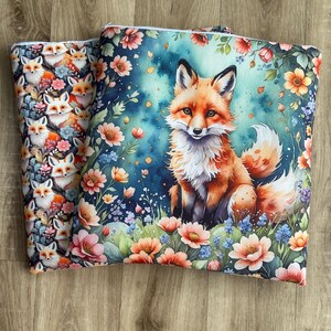 May include: Two decorative pillows with fox designs. One pillow features a repeating pattern of foxes and flowers. The other pillow showcases a watercolor illustration of a fox surrounded by flowers in shades of pink, orange, and blue.