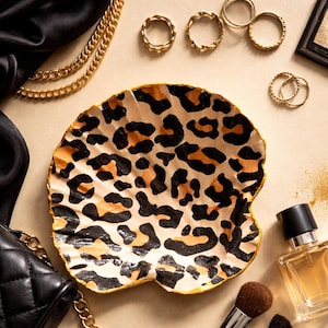 Könnte beinhalten: Eine weiße Keramik-Tasse mit schwarzem Henkel und dem Text "But First, Coffee" in schwarzer, handschriftlicher Schrift. Die Tasse steht auf einer weißen Oberfläche.