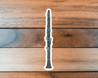 May include: A black clarinet with silver keys and a blue and white design. The clarinet is on a wood background.