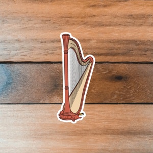 May include: A red wooden harp with a white background. The harp has a white stringed section and a red wooden base.