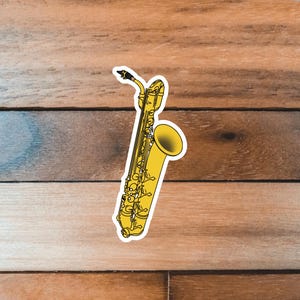 May include: A yellow saxophone with a black mouthpiece and keys. The saxophone is on a woodgrain background.