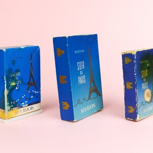 Puede incluir: Tres cajas de perfume vintage azules y doradas con el texto "Soir de Paris" y el logotipo de Bourjois. Las cajas presentan un gr&aacute;fico de la Torre Eiffel.
