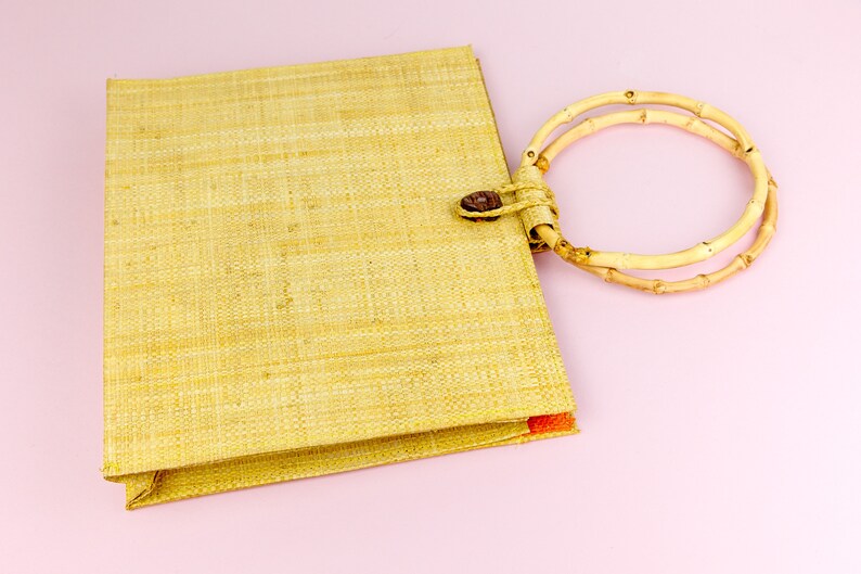 Puede incluir: Un bolso de mano tejido de color marr&oacute;n claro con un asa de bamb&uacute; de doble anillo.