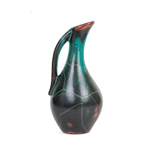 May include: A decorative ceramic jug with a dark, glossy finish. The jug features a teal interior and handle, with a brown rim and base. The exterior has a cracked pattern design.