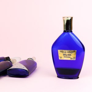 May include: Four blue glass bottles of cologne, one with a gold cap and a label that reads "Eau de Cologne Soir de Paris Bourjois 75* 25 c.c."