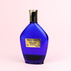 May include: A blue glass bottle of cologne with a gold cap and a gold label that reads "Eau de Cologne SOIR de PARIS BOURJOIS 25 C.C. 75&deg;".