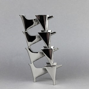 May include: A silver metal sculpture made of stacked, geometric shapes. The sculpture is made up of multiple pieces that are stacked on top of each other, creating a unique and modern design.